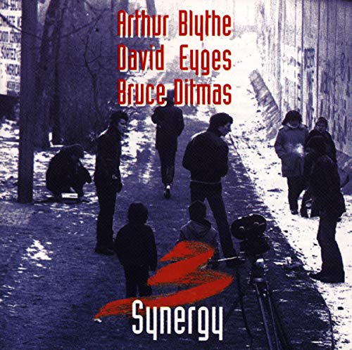 "Album cover with people on a snowy alley, red and white text, and abstract design."