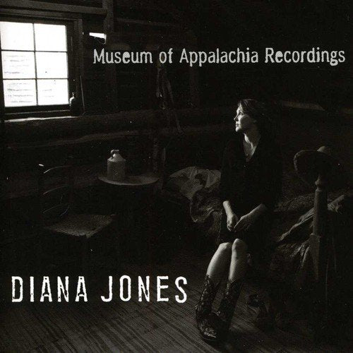 "CD cover featuring a woman sitting in a dimly lit, rustic cabin interior."