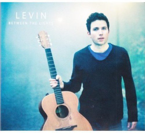 "Album cover featuring a man holding an acoustic guitar, wearing a dark sweater."