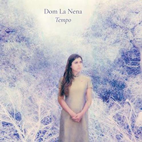 A woman in a beige dress stands in a snowy landscape, album cover.