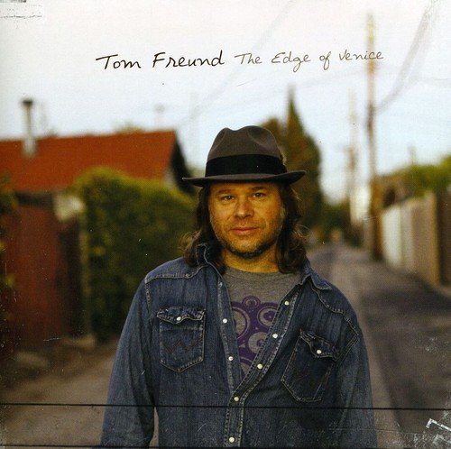 "Album cover featuring Tom Freund standing on a street, wearing a denim shirt and hat."