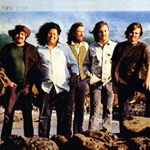"Vinyl record cover featuring a band of five men standing on rocky terrain."