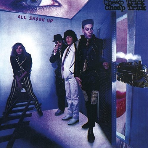 "Album cover featuring four men in a blue room with a train outside."