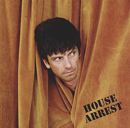 Man peeking through brown velvet curtains with "House Arrest" text on the right.
