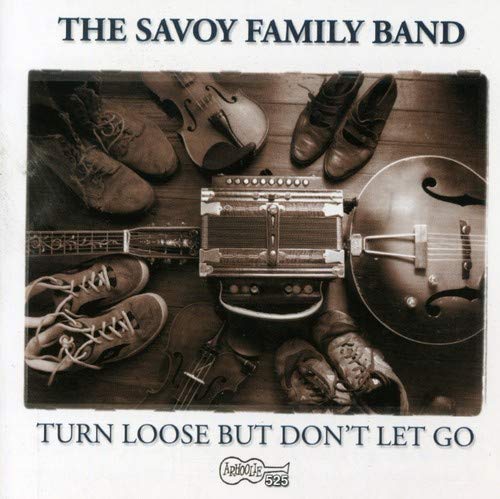 "CD cover with sepia-toned image of shoes and musical instruments on a wooden floor."
