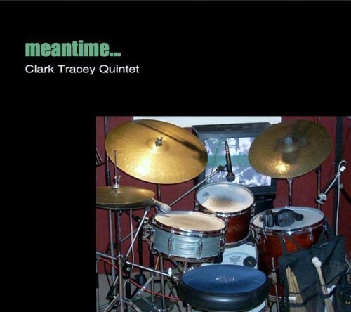 "CD cover featuring a drum kit against a red wall with a window."
