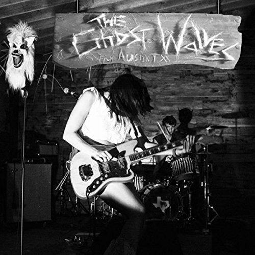 Black and white image of a woman playing guitar on stage with a banner.