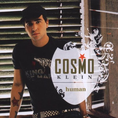 "Album cover featuring a man with tattoos standing in front of window blinds."