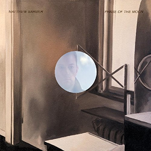 "Album cover with a man reflected in a circular mirror, muted tones."