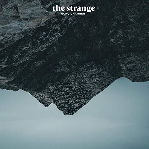 The image depicts a vinyl album cover featuring a dark, rocky cliff against a gray sky.
