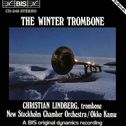 A trombone lies on a snowy surface, on a black album cover.