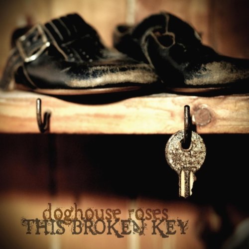 A pair of worn black shoes and a rusty key on a wooden shelf.