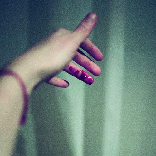 A hand with pink nails is reaching toward a green curtain.
