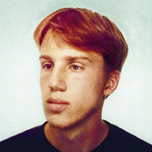 A man with short red hair and a black shirt is shown from the shoulders up.