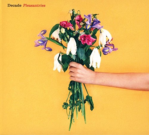 A hand holding a bouquet of white, pink, and purple flowers against a yellow background.