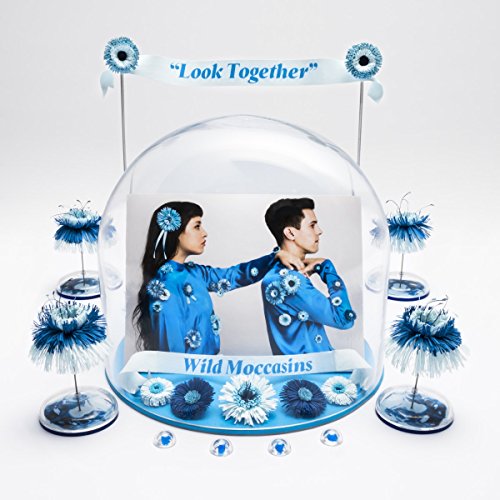 "Album cover with man and woman in blue outfits inside a glass dome."