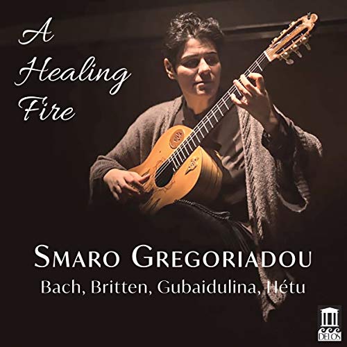 The image depicts a CD cover featuring a man holding a lute. The man is centered, wearing a gray sweater over a dark shirt, and is looking directly at the camera. He holds the lute in his left hand and its neck with his right hand. The title "A Healing Fire" is written in white cursive font to the left of the man's head. Below the man, the text "Smaro Gregoriadou" appears in large white letters, followed by "Bach, Brit