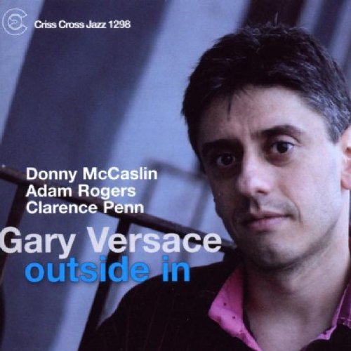 "Album cover featuring a man with short dark hair and a pink shirt."