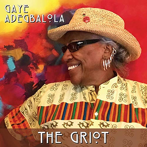 Album cover: smiling woman in straw hat and patterned shirt against a colorful background.