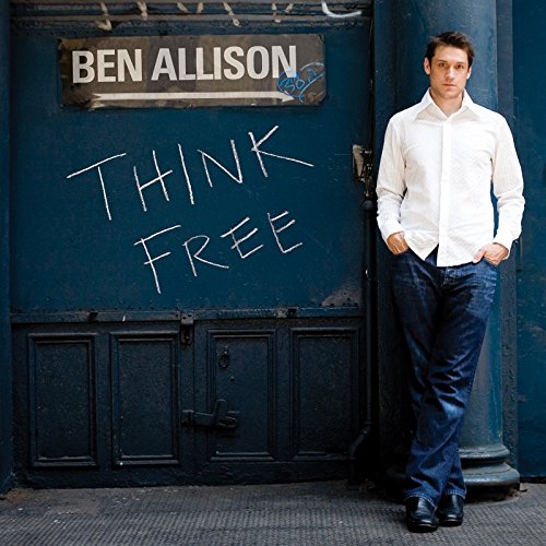 "Album cover with man standing by a blue wall with 'Think Free' written on it."