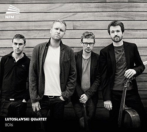 Black and white image of four men standing against a wooden wall.