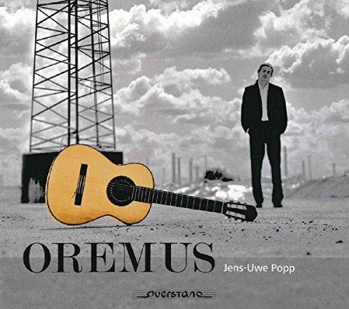 "Album cover featuring a man in a suit and a guitar on the ground."