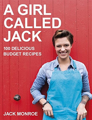 "A woman in a blue apron stands against a red wooden door."