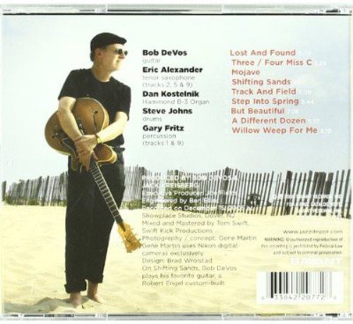 Man holding guitar on beach, with CD tracklist and barcode on the back cover.