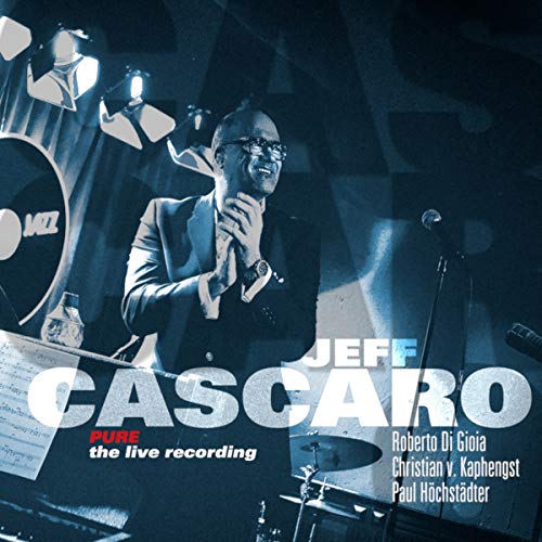 "Album cover featuring a man singing into a microphone on a dark stage."