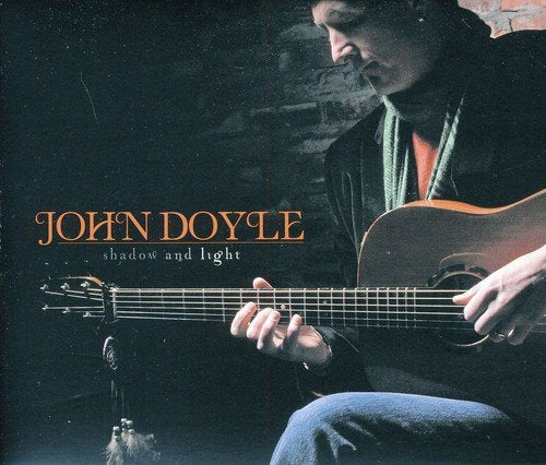 "Album cover featuring a man playing guitar with 'John Doyle Shadow and Light' text."