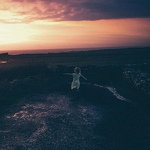 A vinyl record cover featuring a woman standing on a cliff at sunset.