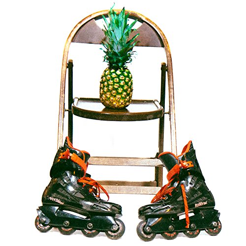 A pair of black rollerblades with orange laces on either side of a metal chair.