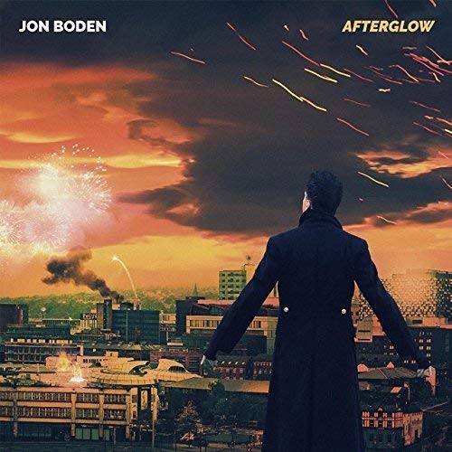The image depicts the vinyl album cover for "Afterglow" by Jon Boden. The alt text is: "Man in a coat standing before a cityscape with fireworks."