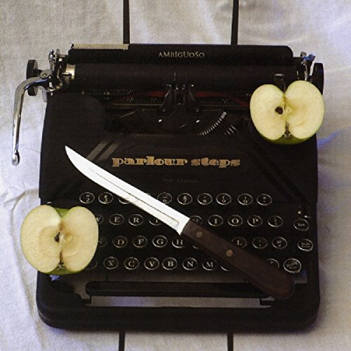 Black typewriter with "parlour steps" on keys, knife, and apple halves on white fabric.