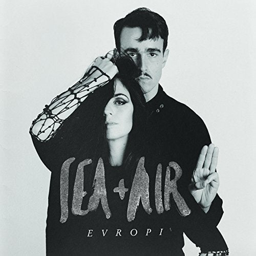 "Black and white album cover with a man and woman in dark clothing."