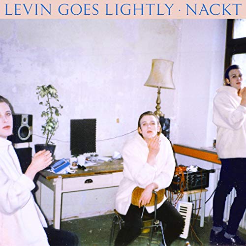 Album cover with three people in white robes in a room with audio equipment.