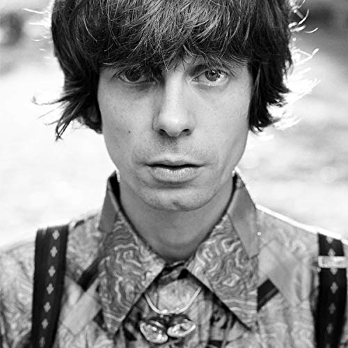 Black and white portrait of a man with shaggy hair and patterned shirt.