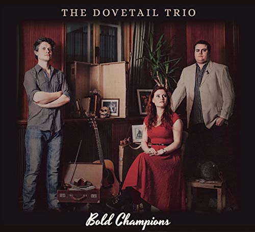 "Album cover featuring three musicians, a woman in red and two men, in a room."