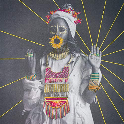 A woman adorned with jewelry, her face obscured by a flower, against a dark background.
