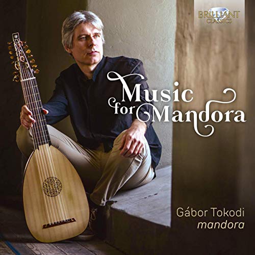 Man sitting on steps holding a mandora, album cover with white and gold text.