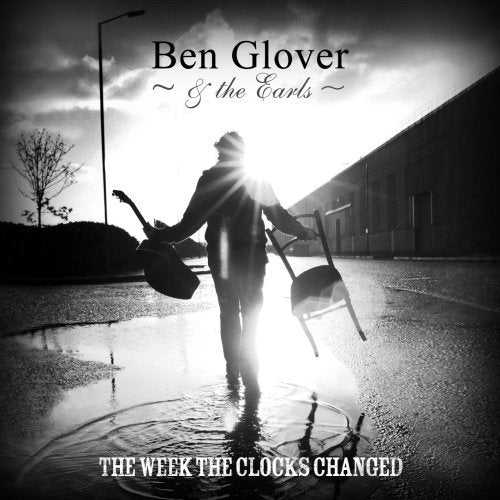 A black and white CD cover featuring a man walking away with a guitar.