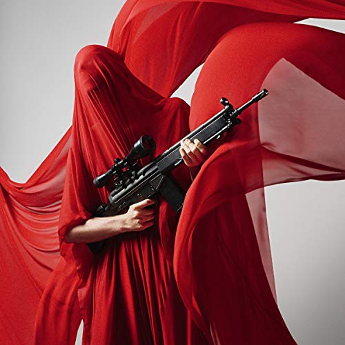 A person in a flowing red garment holds a black rifle against a gray background.