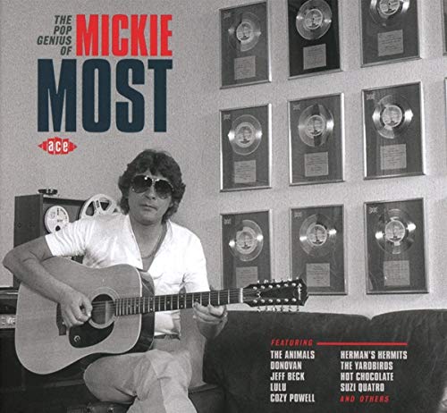 "CD cover with man holding guitar and wall of gold discs."