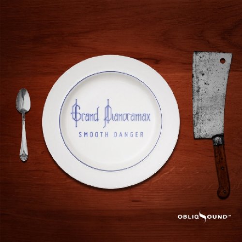 White plate with blue text "Grand Pianoramax Smooth Danger" on a dark wooden table.