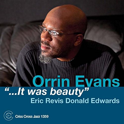 The image is a CD cover featuring a man sitting on a couch. Alt text: "CD cover with a bald man wearing glasses and a black sweater."