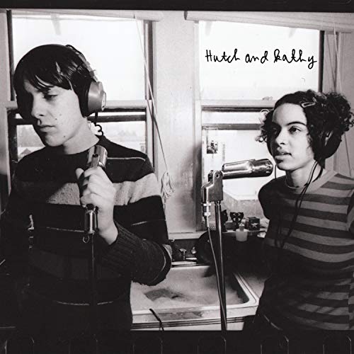 Black and white album cover with man and woman recording in a kitchen.