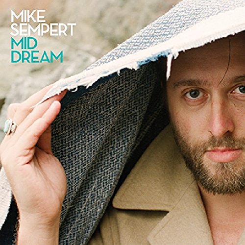 A man with a beard peers from under a torn blanket, album cover art.