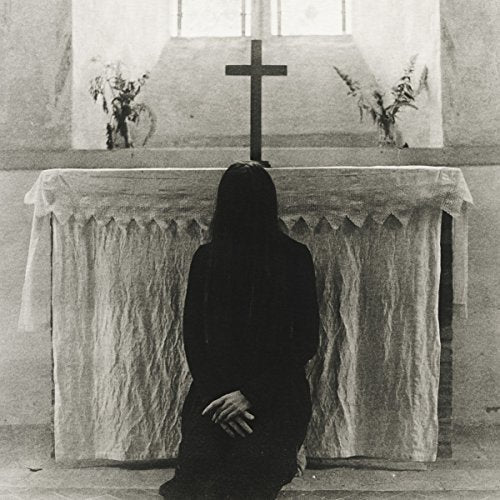 Black and white image of a kneeling figure before an altar with a cross.