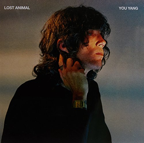 Album cover featuring a man with curly hair and dark jacket, touching his face.