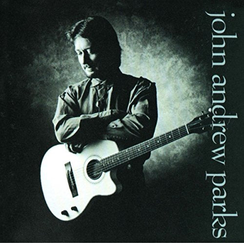"Album cover featuring a man holding a white guitar against a dark background."